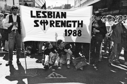 Women holding 'Lesbian Strength 1988' banner, featuring the labrys and downwards triangle.